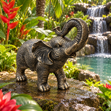 Load image into Gallery viewer, Aged gold polyresin elephant statue with raised trunk in a luxurious garden