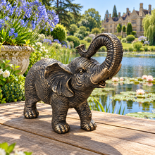 Load image into Gallery viewer, Aged gold polyresin elephant statue with raised trunk in a luxurious garden
