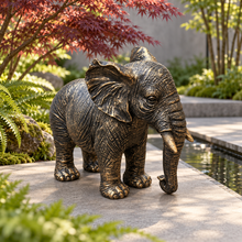 Load image into Gallery viewer, Classic aged gold polyresin elephant with lowered trunk in a luxurious garden
