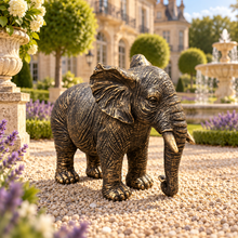 Load image into Gallery viewer, Classic aged gold polyresin elephant with lowered trunk in a luxurious garden
