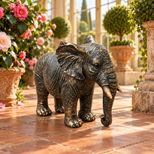 Load image into Gallery viewer, Classic aged gold polyresin elephant with lowered trunk in a luxurious garden
