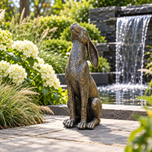 Laden Sie das Bild in den Galerie-Viewer, Moon gazing hare ornament in aged gold finish beside a garden waterfall
