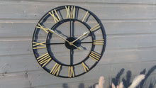 Indlæs og afspil video i gallerivisning Black Skeleton frame outdooor/Indoor clock with gold hands and gold numerals
